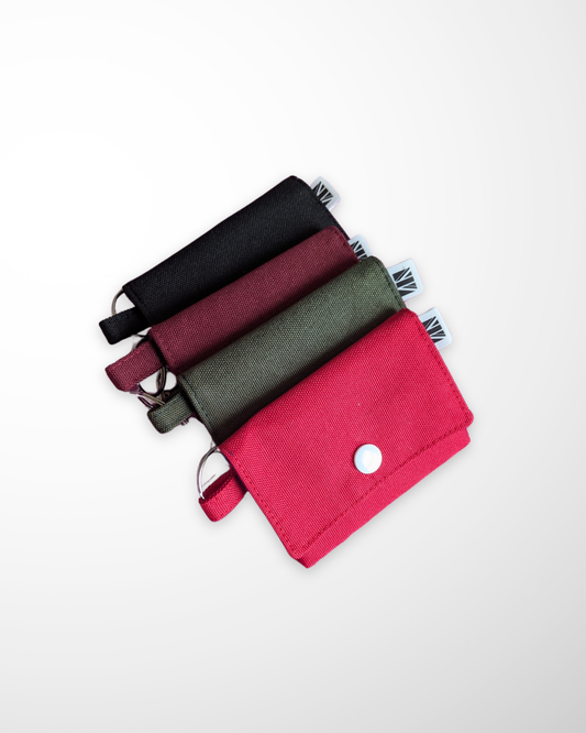 Set of four water resistant canvas card holders with keychain tabs, in black, burgundy, khaki green, and red on a white background.
