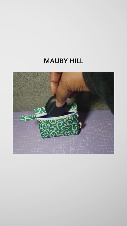 Hand putting earphones into a teal and white patterned pouch